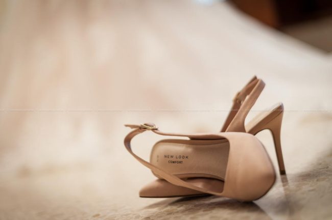 Photo of the bridal shoes, with the wedding dress in the background