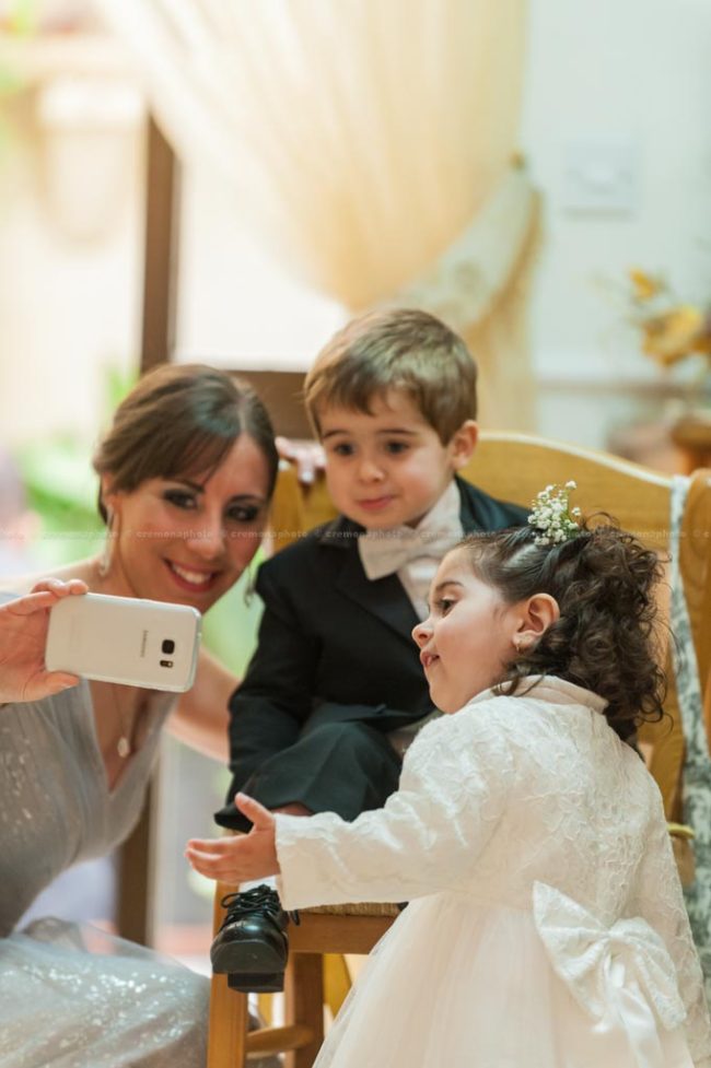 A wedding bridesmaid showing a picture she just took to her toddler nephew and niece