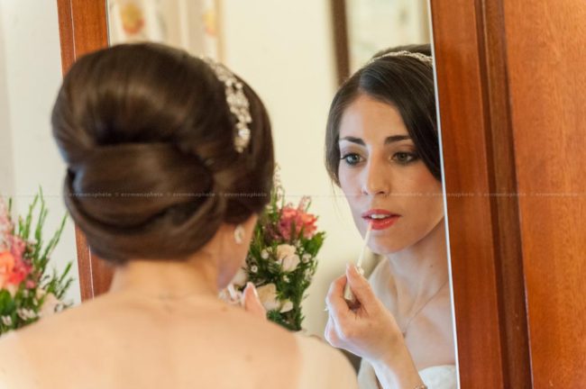 The bride applying a final touch of make up prior to leaving her home to get married in Gozo