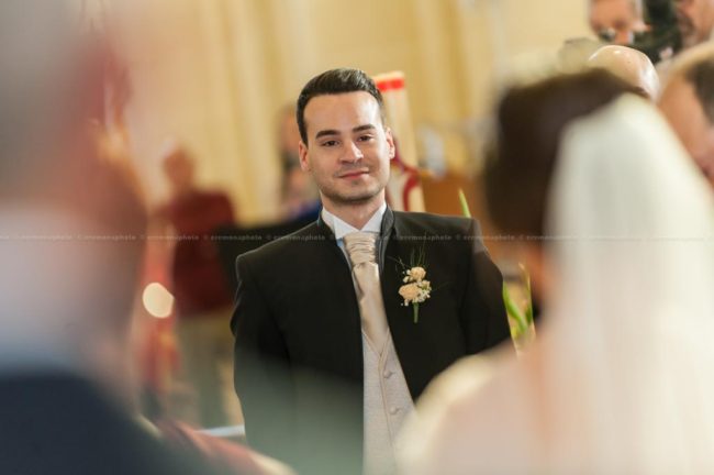 Red eyes betraying groom's emotion while his bride is walking down the aisle prior to wedding.